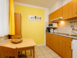 a kitchen with a table and a yellow wall at Apartment Dünenhaus App- 104 by Interhome in Zempin