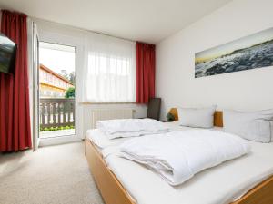 a white bedroom with a large white bed and a window at Apartment Dünenhaus App- 104 by Interhome in Zempin