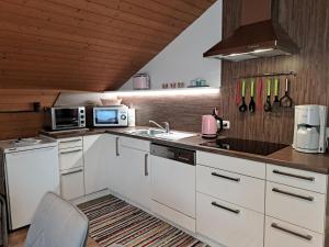 een keuken met witte kasten, een wastafel en een magnetron bij Apartment Schragl - MHO487 by Interhome in Ginzling