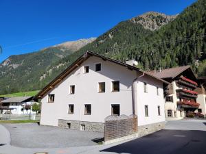 a white building with mountains in the background at Holiday Home Ferienhaus Gaugg by Interhome in Sankt Leonhard im Pitztal