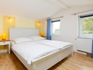 een wit bed in een kamer met 2 ramen bij Holiday Home Delphin by Interhome in Zinnowitz