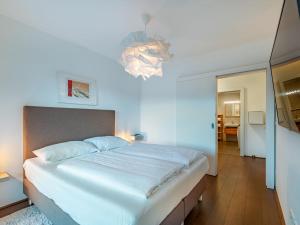 een slaapkamer met een groot wit bed en een kroonluchter bij Apartment Seetraum alpe maritima Ski & See Top 3 by Interhome in Annenheim