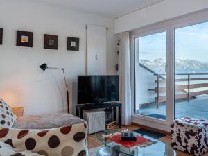 a living room with a tv and a large window at Apartment Olympic C7 by Interhome in Nendaz