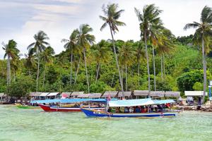 three boats on the water with palm trees in the background at POP! Hotel Tanjung Karang in Bandar Lampung