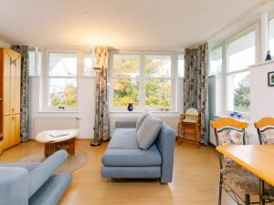 ein Wohnzimmer mit einem blauen Sofa und Fenstern in der Unterkunft Apartment Dünenresidenz 24 by Interhome in Zinnowitz