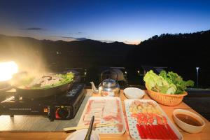 stół z talerzami jedzenia i grill w obiekcie สวนไร่รุ่งอรุณ w mieście Ban Na Pa Paek