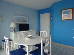 Un comedor azul con una mesa y sillas blancas. en Apartment Pamplemousse Face Mer by Interhome, en Les Bains