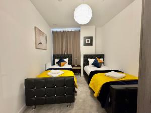 um quarto com 2 camas com almofadas amarelas e azuis em 3Bedroom, 2Bathroom, Balcony,Luxury Flat Westfield em Londres