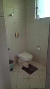 a bathroom with a toilet in a white tiled room at Blu Hostel in Blumenau