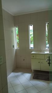 a white bathroom with a sink and two windows at Blu Hostel in Blumenau