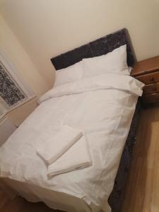 a bed with white sheets and pillows on it at Single Room near London Seven Kings Train station in London