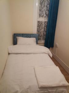 two beds in a small room with a window at Nice Single Room near London Seven Kings Train station in London