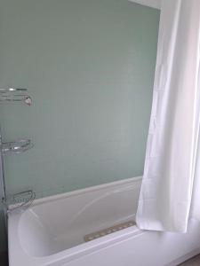 een wit bad met een douchegordijn bij Nice Single Room near London Seven Kings Train station in Londen