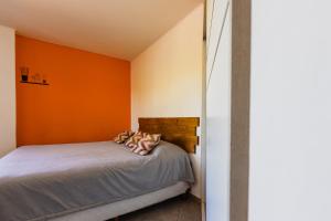 Un dormitorio con una pared de color naranja y una cama en Céntrico Departamento Tangerine San Rafael en San Rafael