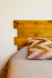Cama con cabecero de madera y almohada en Céntrico Departamento Tangerine San Rafael en San Rafael