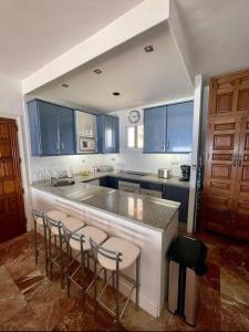 a kitchen with blue cabinets and a bar with stools at Bungalow Calma La Roca 59 in Torremolinos +7 photos