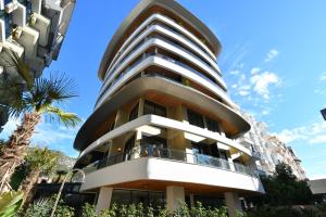 a building with a circular facade with a palm tree at Litore 1 room 200 m sea in Alanya