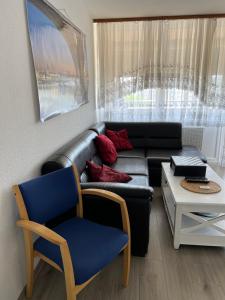 ein Wohnzimmer mit einem Ledersofa und einem Stuhl in der Unterkunft Apartment in Mainz-Lerchenberg in Mainz