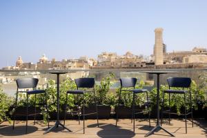 a group of chairs and tables on a balcony at 19 ROOMS in Valletta