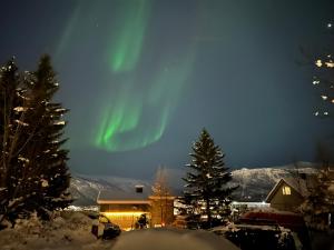 Eine Aurora tanzt am Himmel über einem Haus in der Unterkunft Arctic 3 room apartment - Aurora View - Free Parking in Tromsø