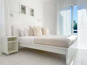 a white bedroom with a white bed and a window at Phaedrus Living Azure Serenity Villa in Khlorakas