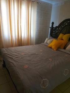 uma cama com almofadas amarelas num quarto com uma janela em Mrembo Lovely Nest em Nairobi