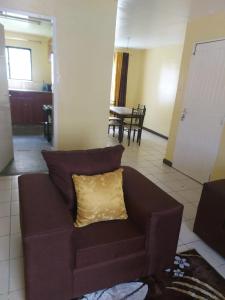 a brown couch with a yellow pillow in a living room at Mrembo Lovely Nest in Nairobi