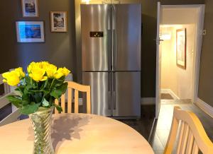 a vase of yellow flowers on a table with a refrigerator at Spacious Georgian Apartment, Central Barnard Castle. in Barnard Castle
