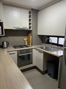 a kitchen with white cabinets and a stove and a sink at Condominio Costa Pucon in Pucón