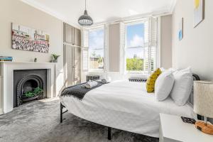 a white bedroom with a large bed and a fireplace at Pass the Keys Luxury Converted Victorian Flat in Leafy Highbury in London