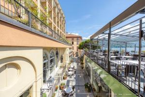 un balcone di un edificio con tavoli e sedie di Hotel Bazzoni a Tremezzo