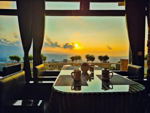 einen Tisch in einem Restaurant mit Blick auf den Sonnenuntergang in der Unterkunft Hotel Poles Apart in Shillong