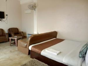 a bedroom with a bed and a couch and a chair at FALL VIEW HOMESTAY in Cherrapunji