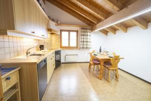 a kitchen with a wooden table and a wooden ceiling at Chasa Sur Chafarrer in Scuol