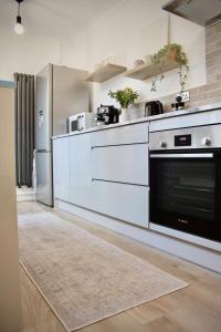 a kitchen with white cabinets and a black oven at Carlton House, 3 Bedroom, Cinema, Mini golf, Wifi in Spinney Hill