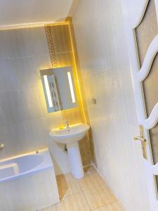 uma casa de banho branca com um lavatório e um espelho em فيلا بحمام سباحه em Cidade 6 de Outubro