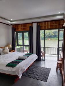 a bedroom with a large bed with a large window at Nam ou view villa in Nongkhiaw