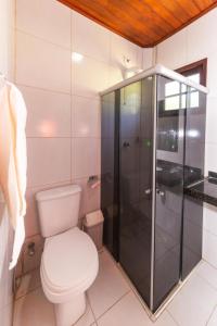 a bathroom with a toilet and a glass shower at Residencial Maragogi in Maragogi