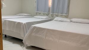 two beds in a room with white sheets at Casa na Praia de Ponta Negra in Natal