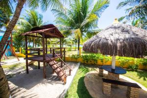 ein Resort mit einem Spielplatz und einem Strohdach in der Unterkunft Residencial Maragogi in Maragogi