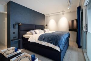 a bedroom with a large bed with a blue wall at Captains Boathouse Studio in Harderwijk