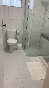 a bathroom with a toilet and a glass shower at Casa na Praia de Ponta Negra in Natal