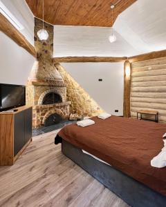 a bedroom with a large bed and a stone fireplace at Ліс&More in Glebovka