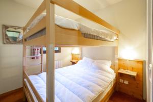 a bedroom with two bunk beds with white sheets at Appart valfrejus in Modane