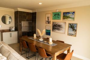 ein Wohnzimmer mit einem Holztisch und Stühlen in der Unterkunft Deja Blue Beachfront Villa, Newly renovated in Langstrand