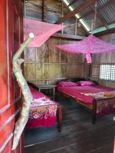 a room with two beds with pink sheets and a tree at Fat Rabbit Beach Resort in Kep