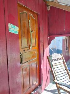 ein rotes Gebäude mit einer Holztür und einem Stuhl in der Unterkunft Fat Rabbit Beach Resort in Kep