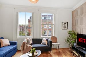 Delightful Flat in London - Sleeps 6 في لندن: غرفة معيشة مع أريكة زرقاء ونوافذ