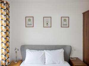 a bedroom with a bed with three pictures on the wall at Pass The Keys - Homely flat in east London with sunny Balcony in London