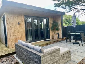 a patio with a couch and a table on a deck at 1 bedroom rural cabin retreat with hot tub in Hambrook close to Bristol city centre in Bristol